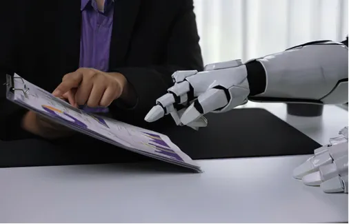 A human hand reviewing a report beside a robotic hand — the human-AI collaboration this primer session grounds in vocabulary